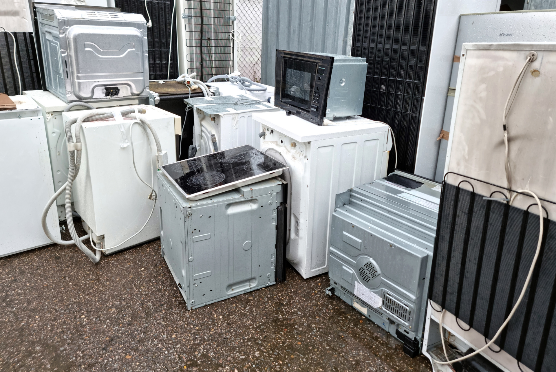 A bunch of old appliances are stacked on top of each other on the ground.