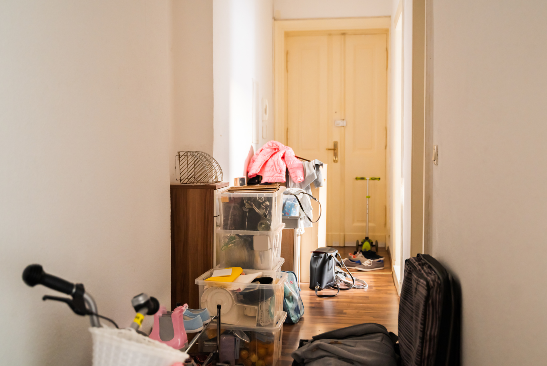 A hallway filled with boxes , a bicycle , and a suitcase.