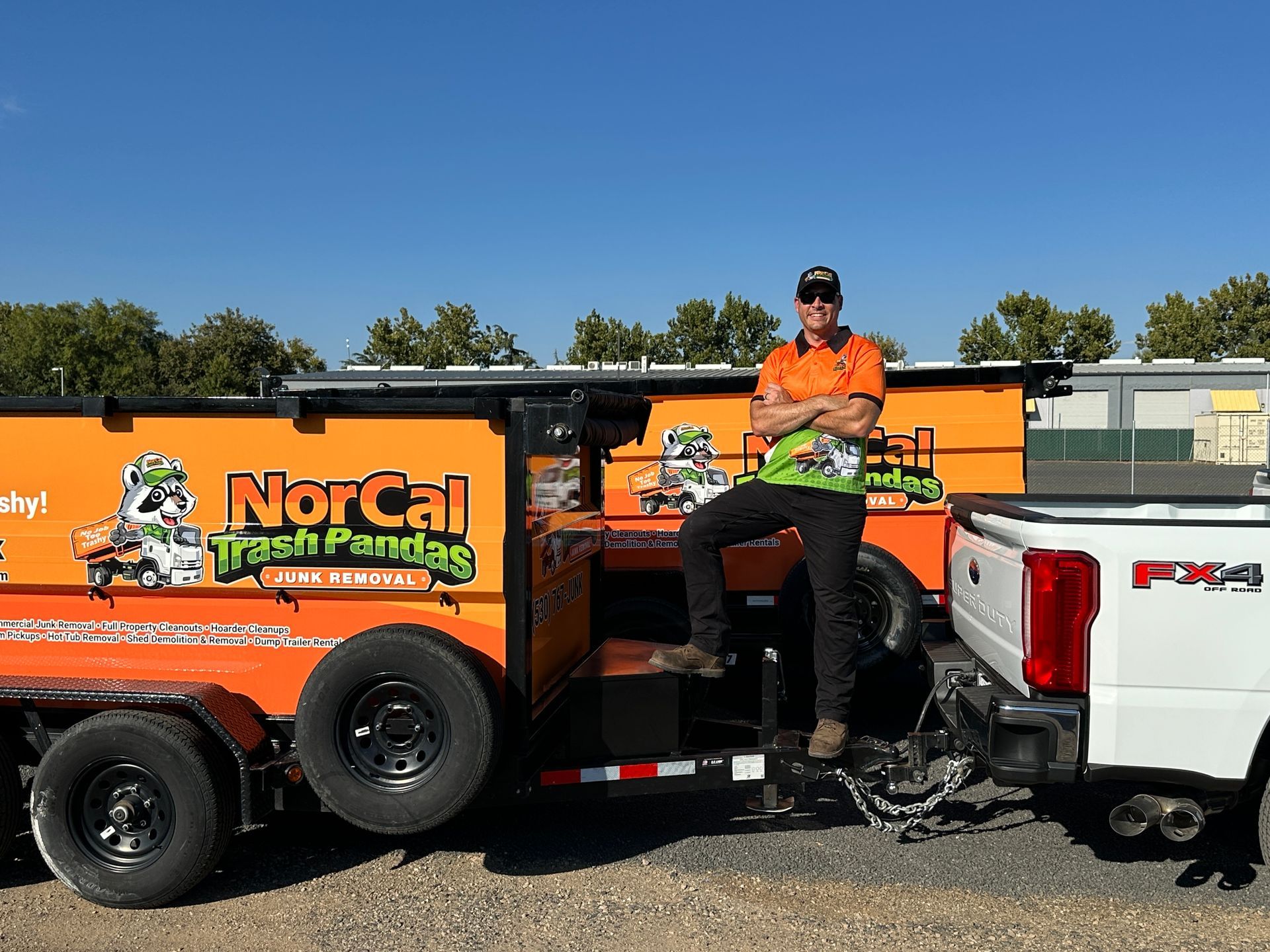 A man is standing in front of a truck with his arms crossed.