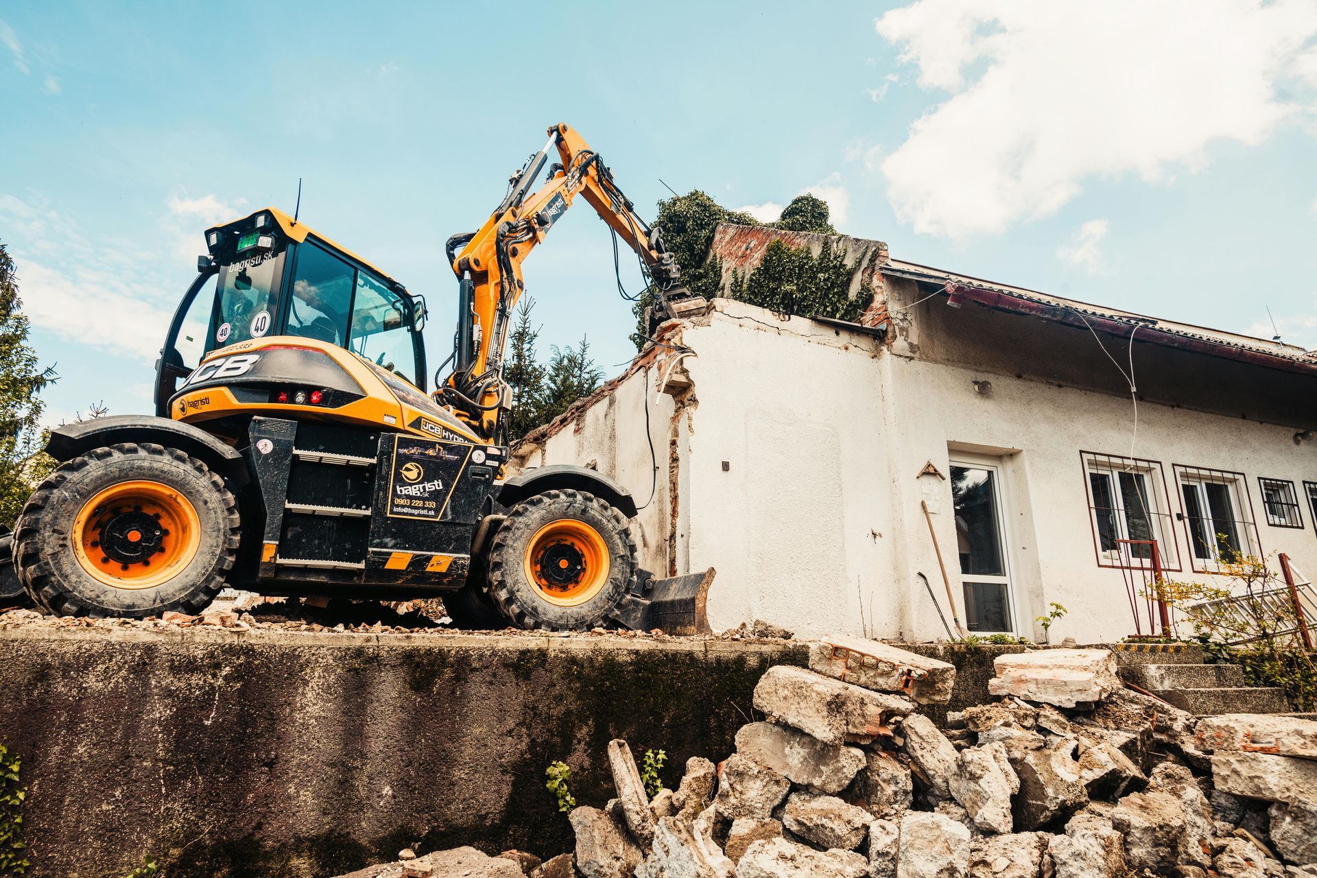 A yellow and black excavator is demolishing a building.