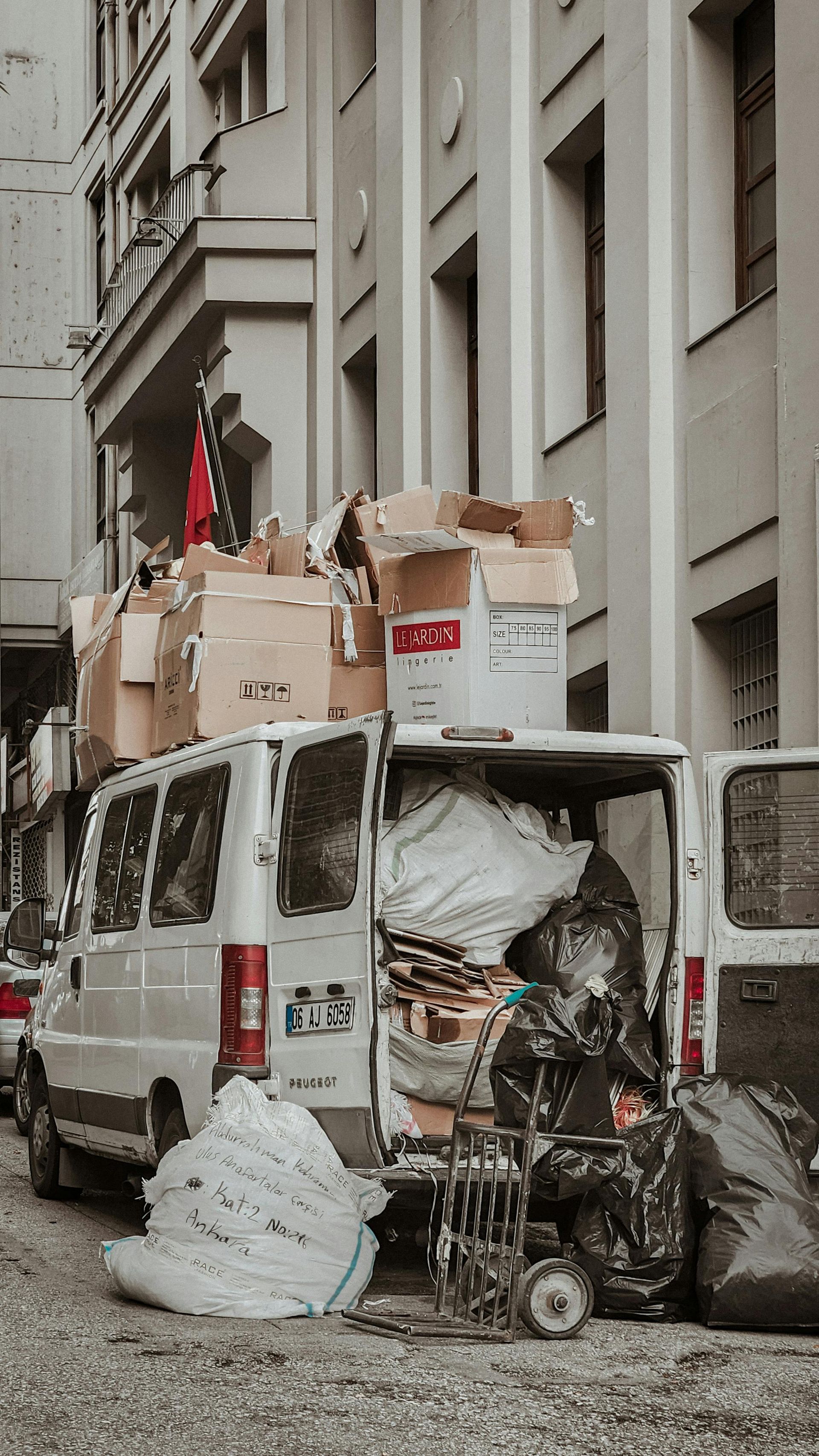 A white van filled with boxes is parked in front of a building.