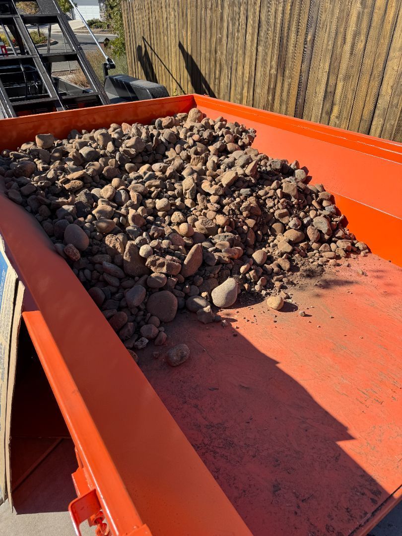 A pile of leaves is sitting in the grass in front of a wooden fence.