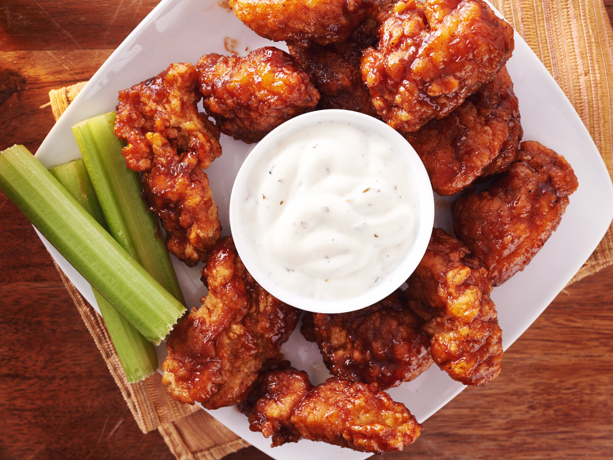A plate of chicken wings with celery and ranch dressing