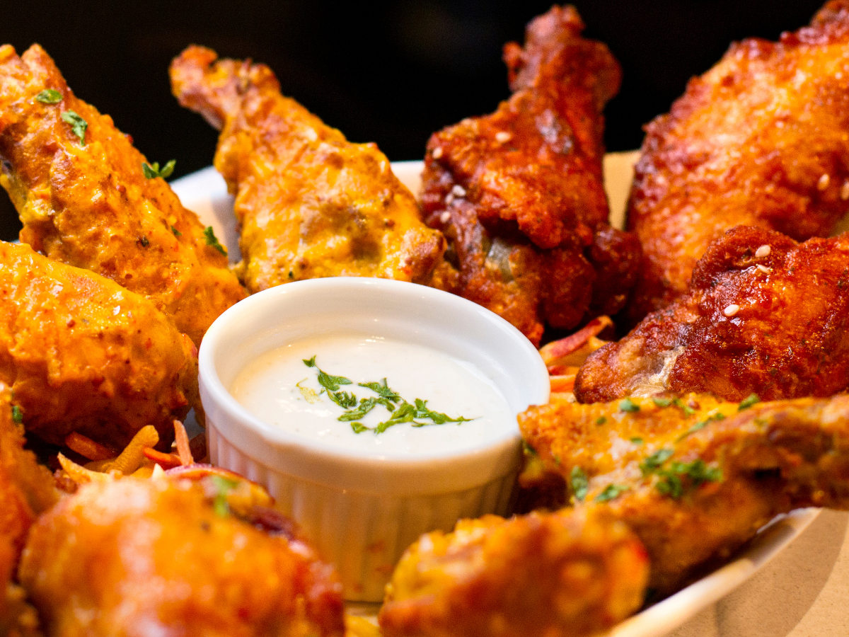 Plate of fried chicken wings with a small bowl of white dip.