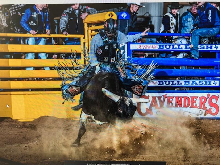 Bull rider on a bucking bull at a rodeo, dust flying, blue and yellow arena.