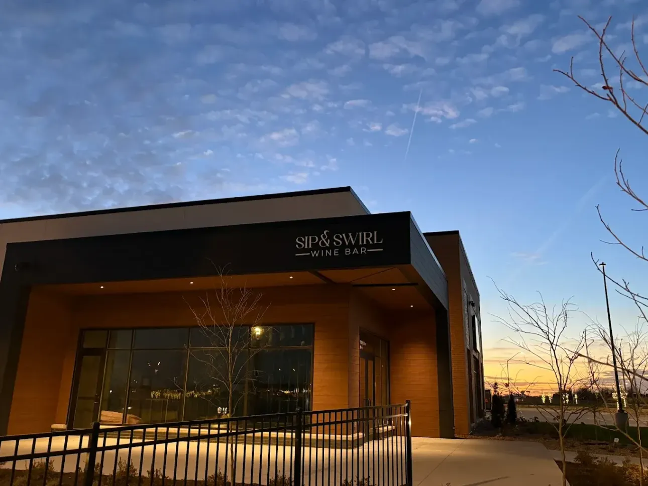 Modern building exterior under a twilight sky; sign reads 