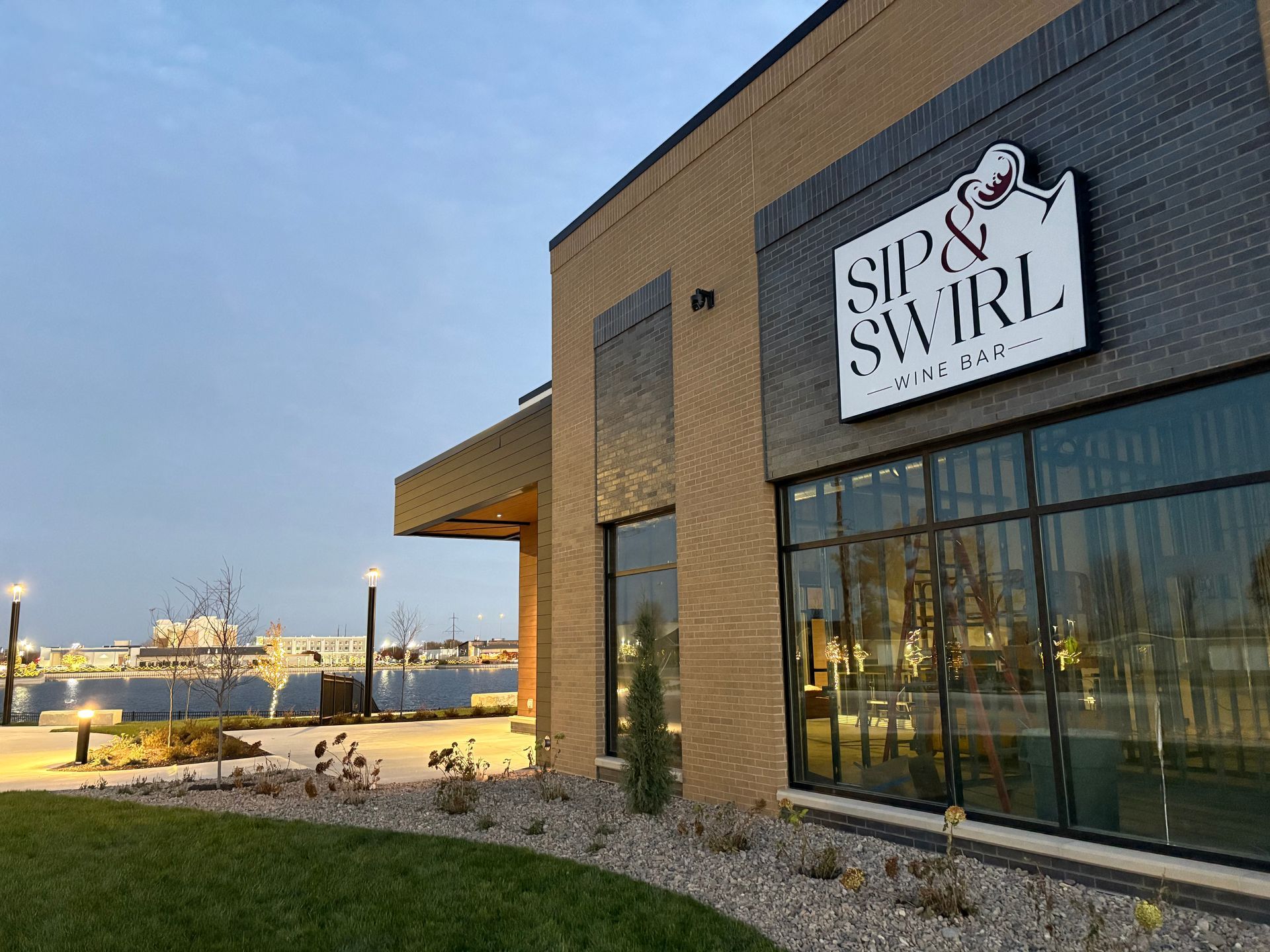 Woman at a bar tasting red wine. Bartender in white shirt and apron watches. Low lighting.