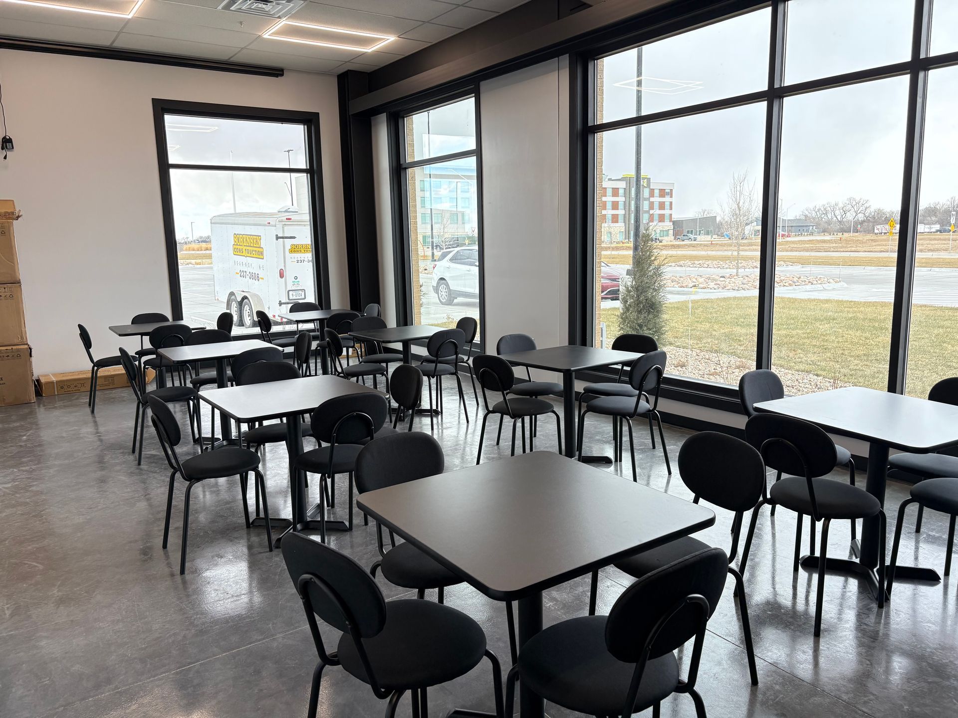 Wooden dining tables set with glassware, napkins, and floral centerpieces; interior setting.