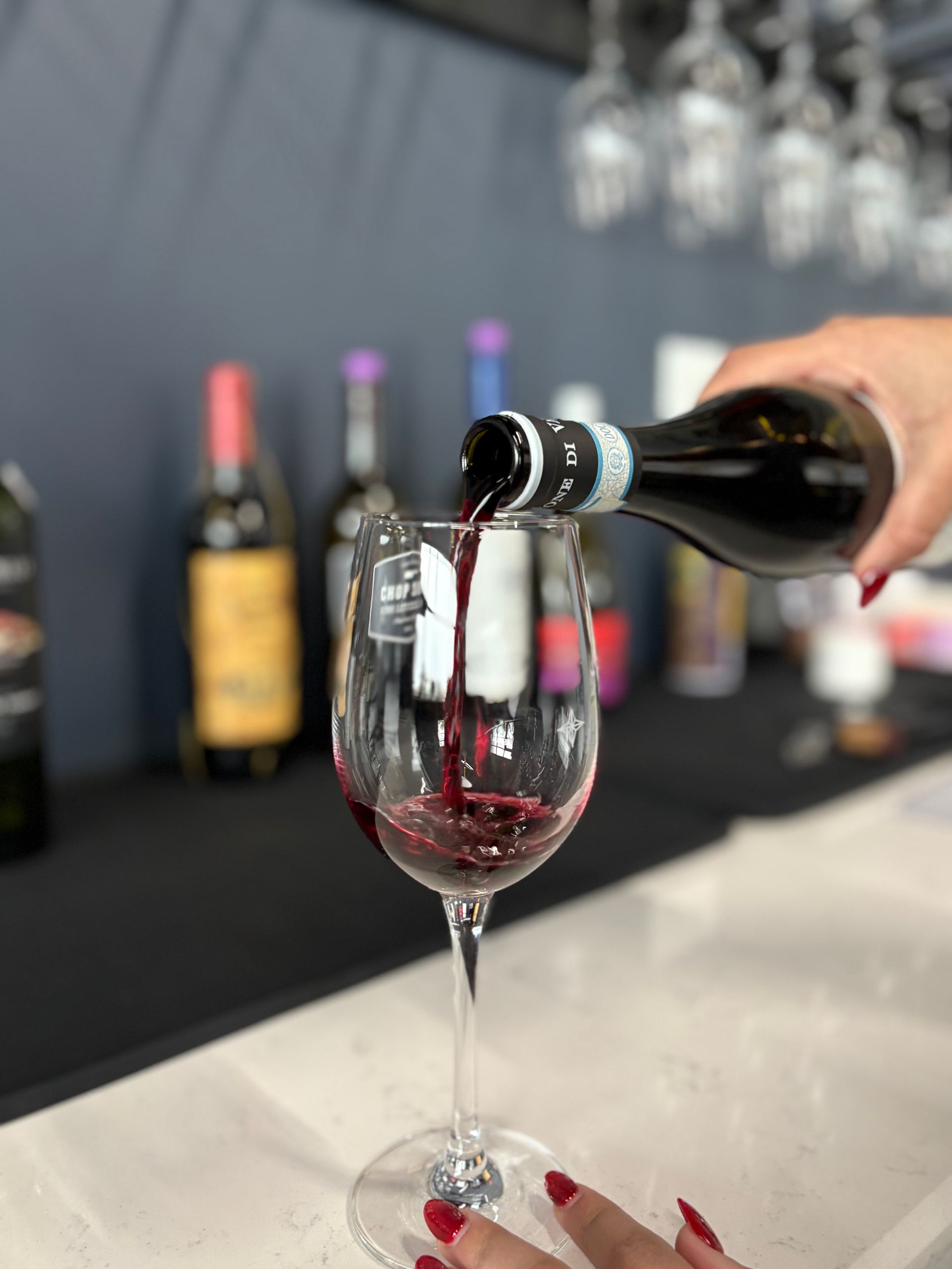 People toasting with wine glasses at a candlelit dinner, with food and a bottle of wine on the table.