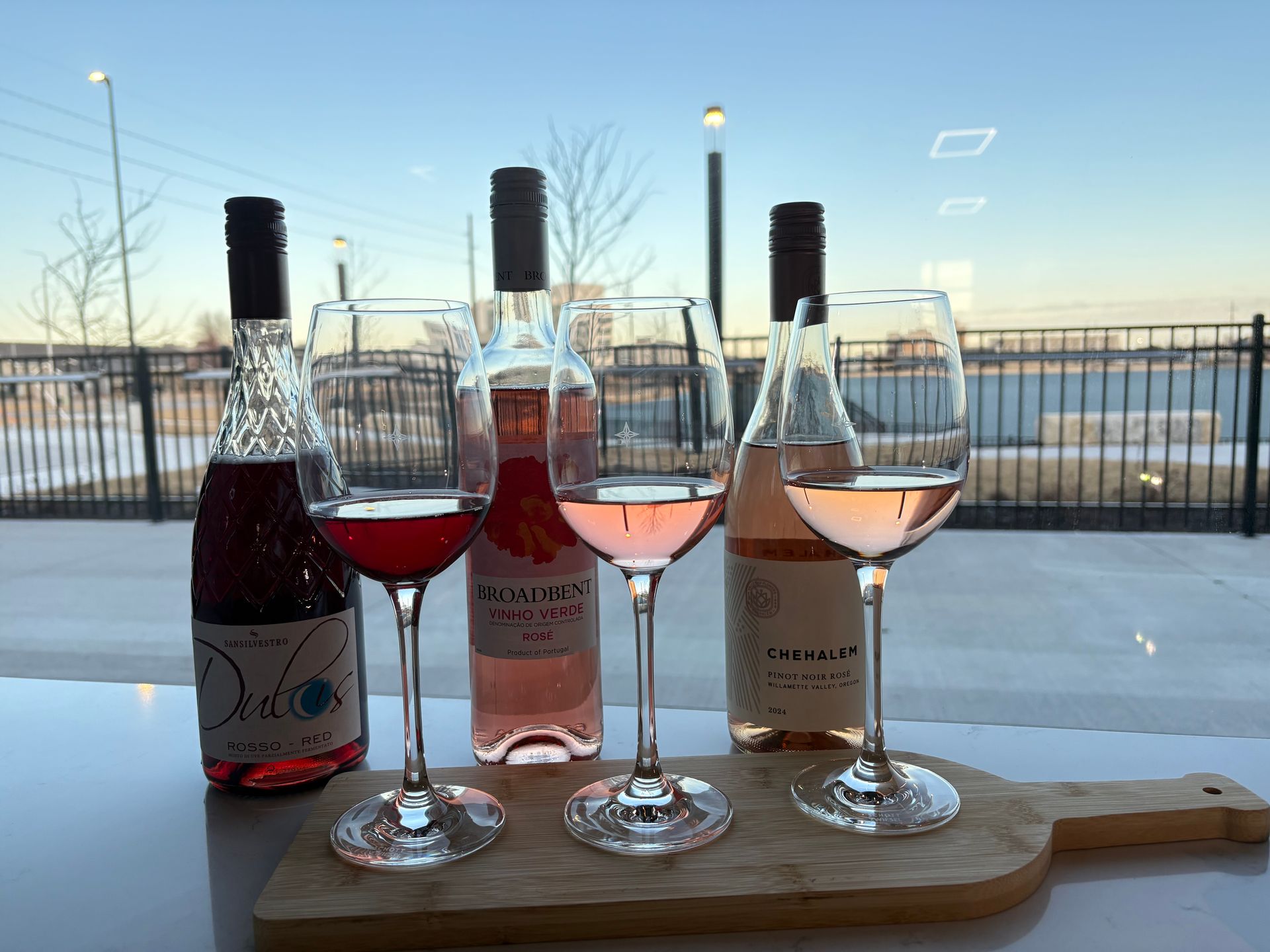 Wine, cheese, and figs on a table. A glass of pink wine stands beside the bottle.