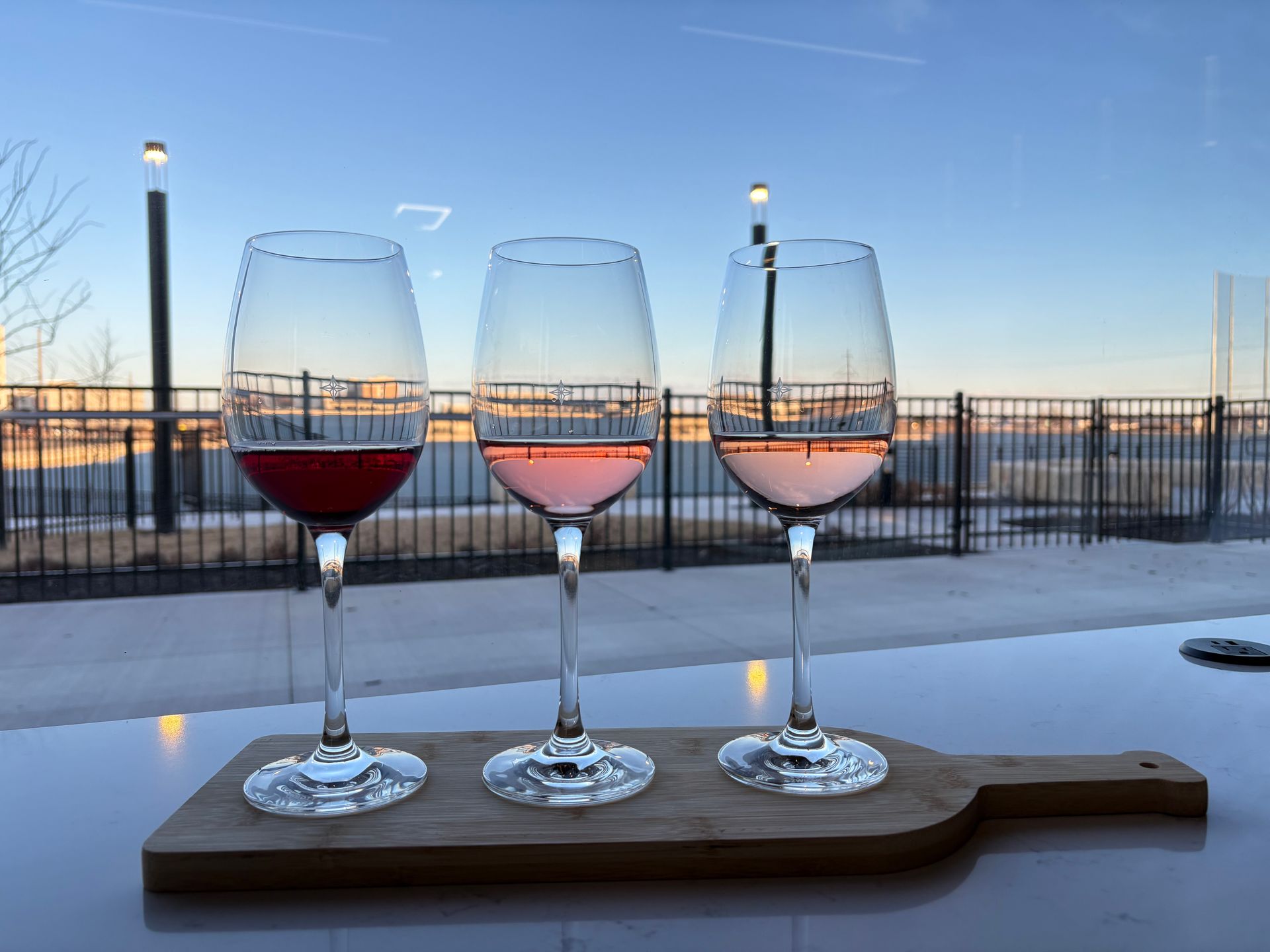 People toasting with wine glasses at a candlelit dinner, with food and a bottle of wine on the table.