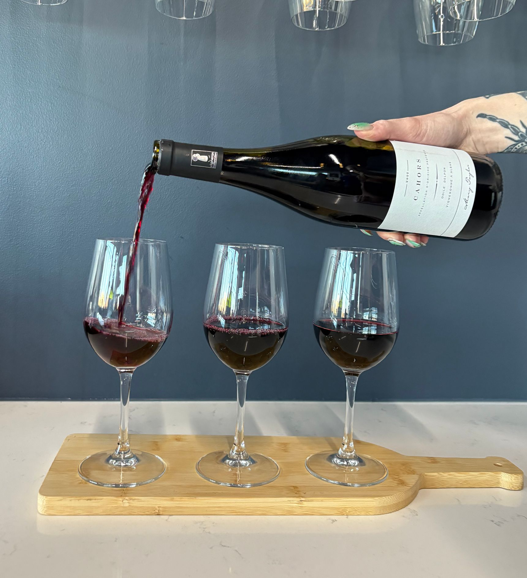 People toasting with wine glasses at a candlelit dinner, with food and a bottle of wine on the table.