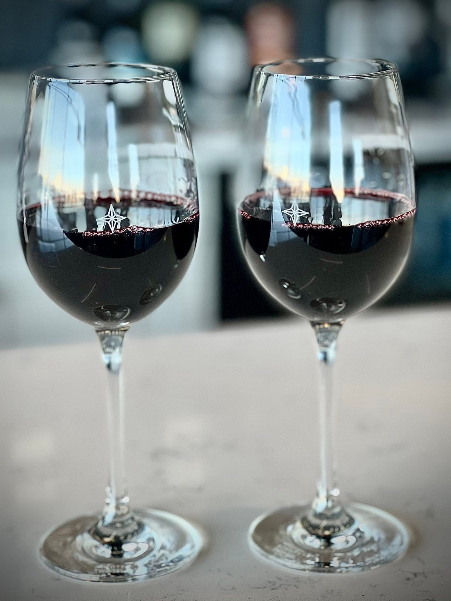 Two wine glasses clink over a charcuterie board and appetizers at a restaurant table.