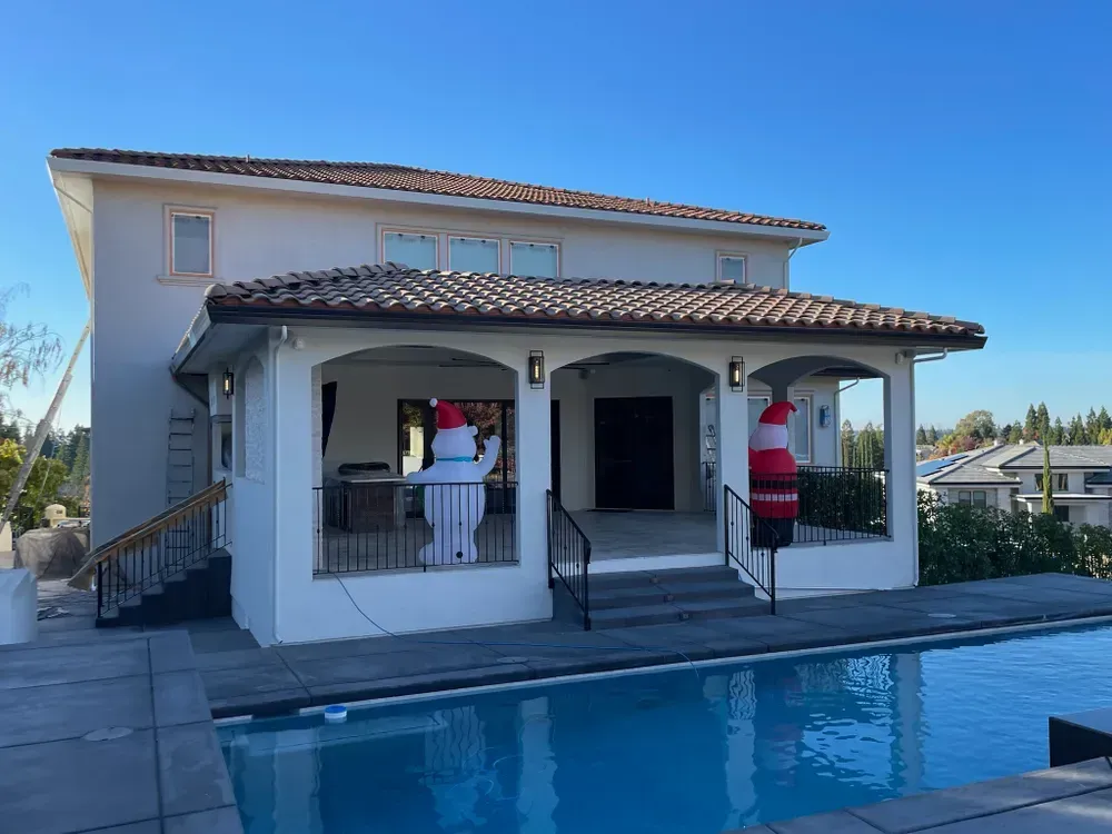 Backyard with a swimming pool, a two-story house, and inflatable Christmas decorations.