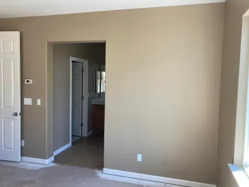 Beige-painted room with white door and doorway to a bathroom.