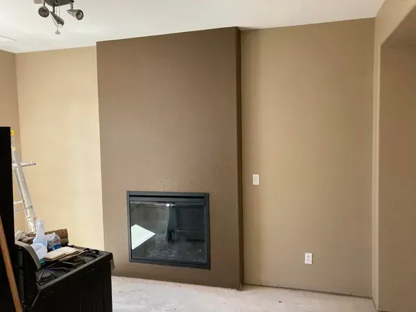 Fireplace in a room with brown and beige walls. A dark square surrounds the fireplace.
