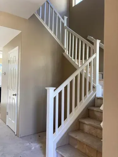 Staircase with white railing and beige wall, leading to a higher level.