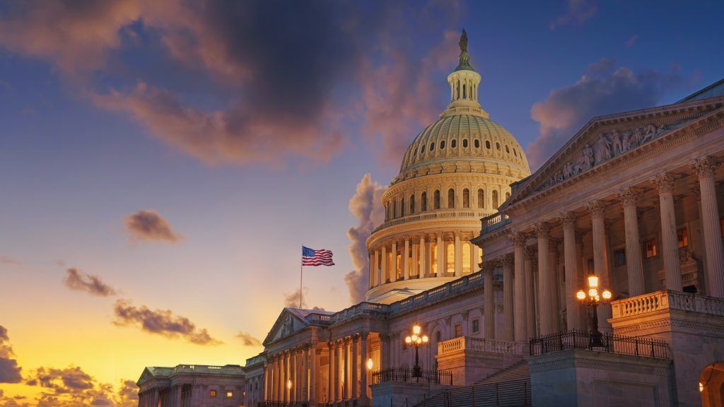 The capitol building in washington d.c. at sunset with a flag flying in front of it.