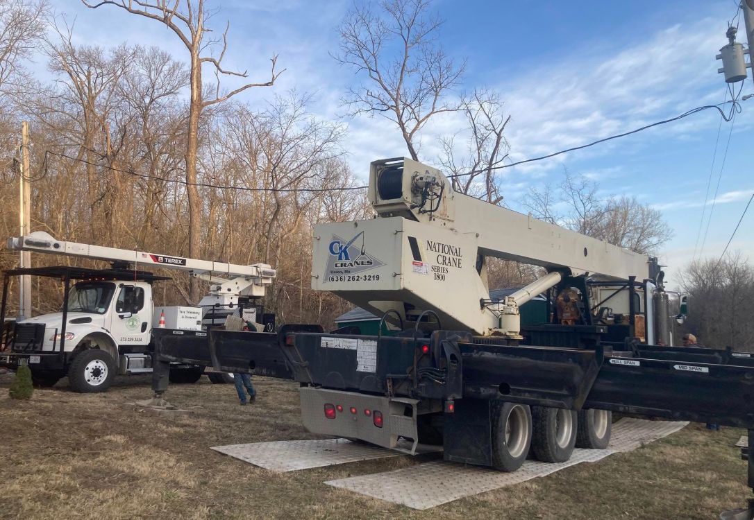A crane is sitting on the back of a truck in a field.