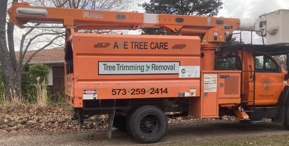 A tree trimming truck is parked in front of a house.