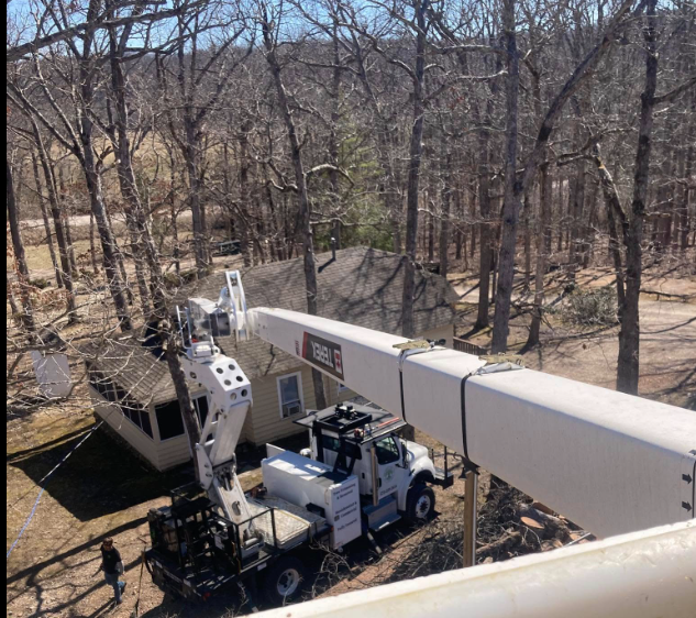 A white truck is parked in front of a house in the woods.