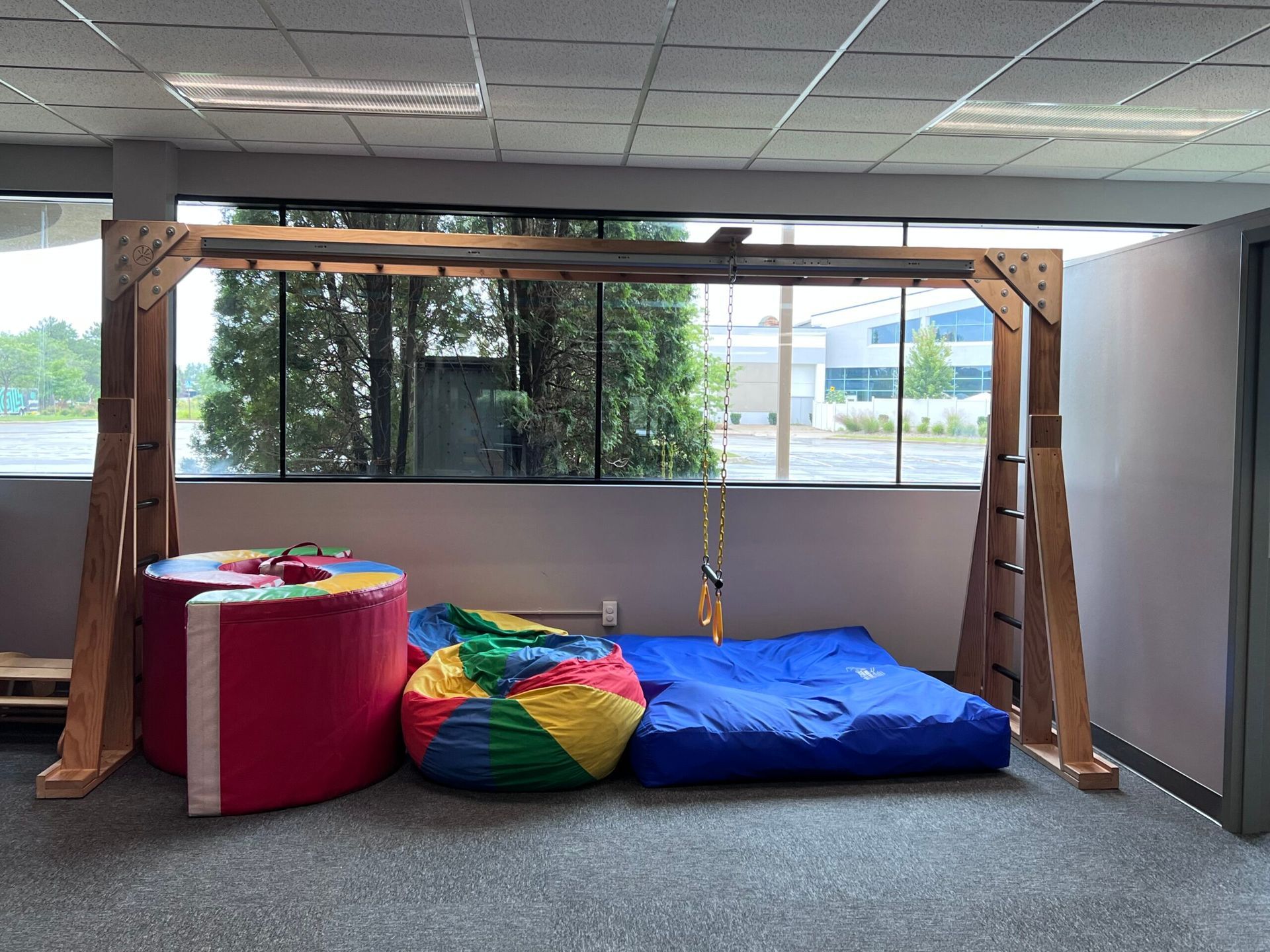 A room with a monkey bars , bean bag chairs , and a blue mat.