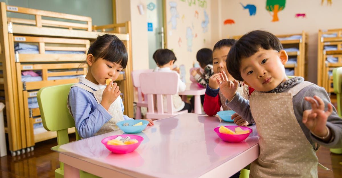 A group of children are sitting at a table eating food.