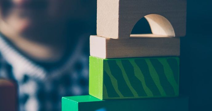 A person is playing with a stack of wooden blocks.