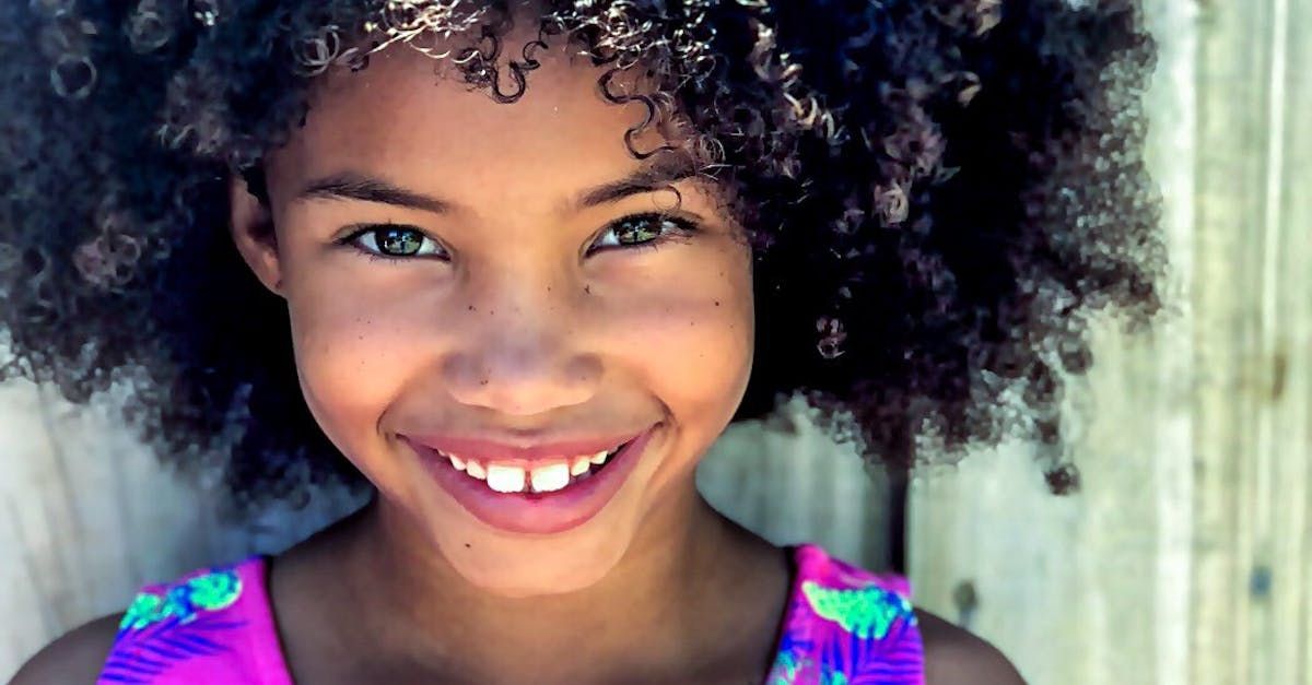 A young girl with curly hair is smiling for the camera.