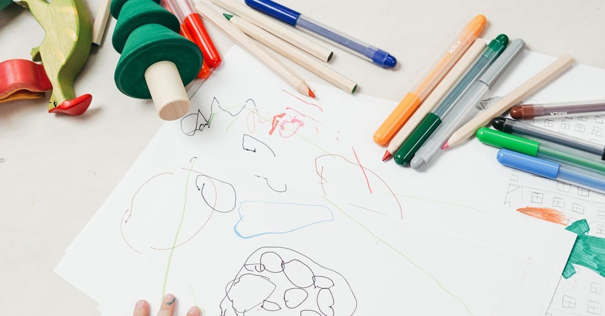 A child is drawing on a piece of paper with markers and pencils.