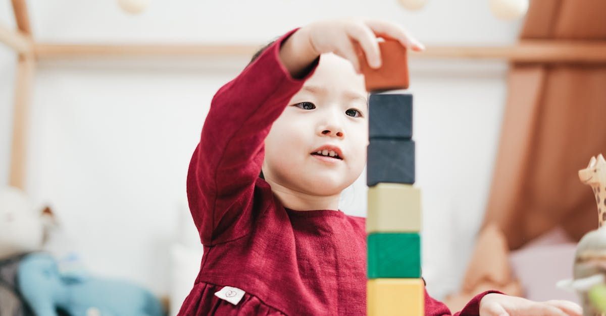 A little girl is playing with wooden blocks in a room.