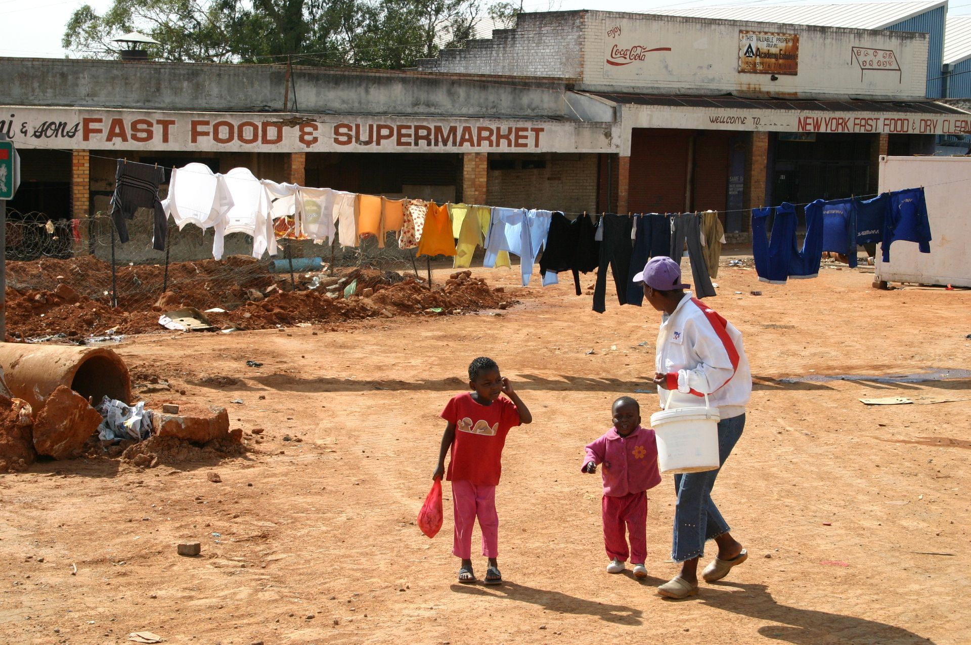 A man and two children are walking in front of a fast food 's supermarket