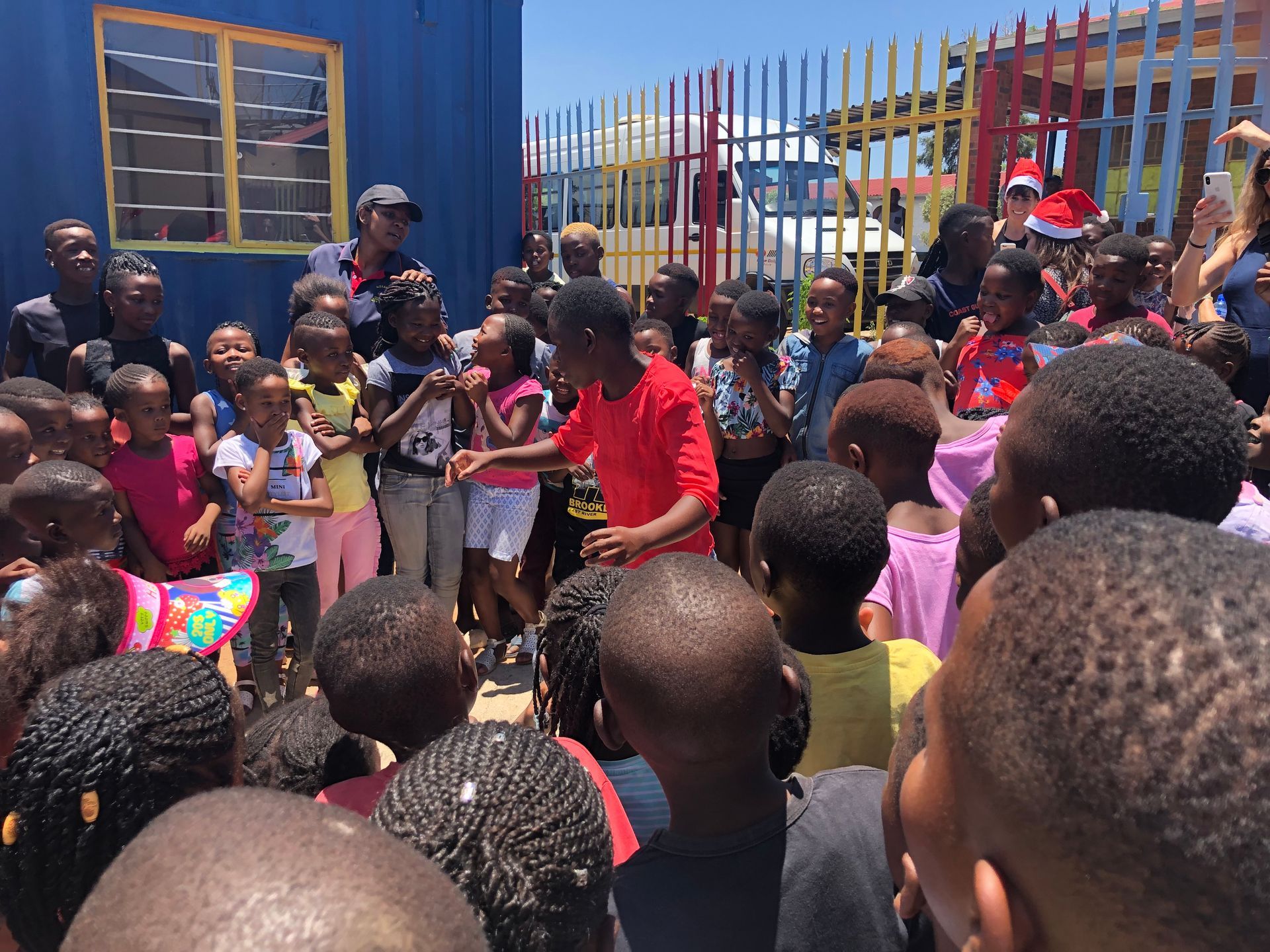 A group of children are standing in front of a blue building.