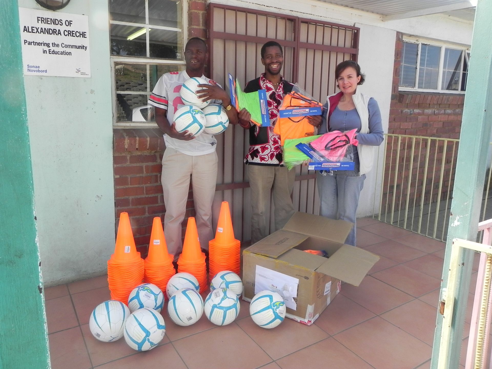 A group of people standing in front of a box of soccer balls