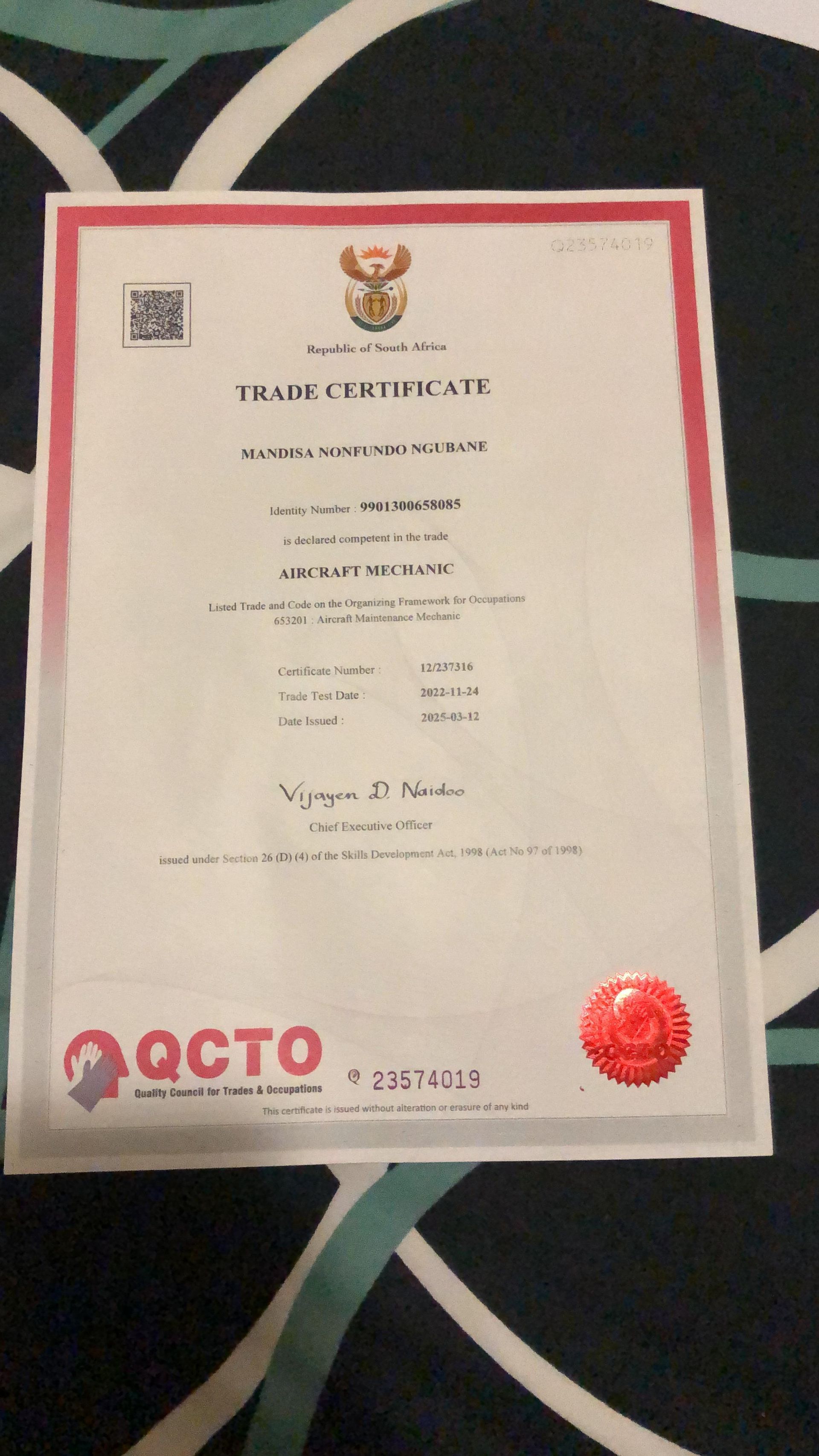 A certificate with a red seal is sitting on a bed.