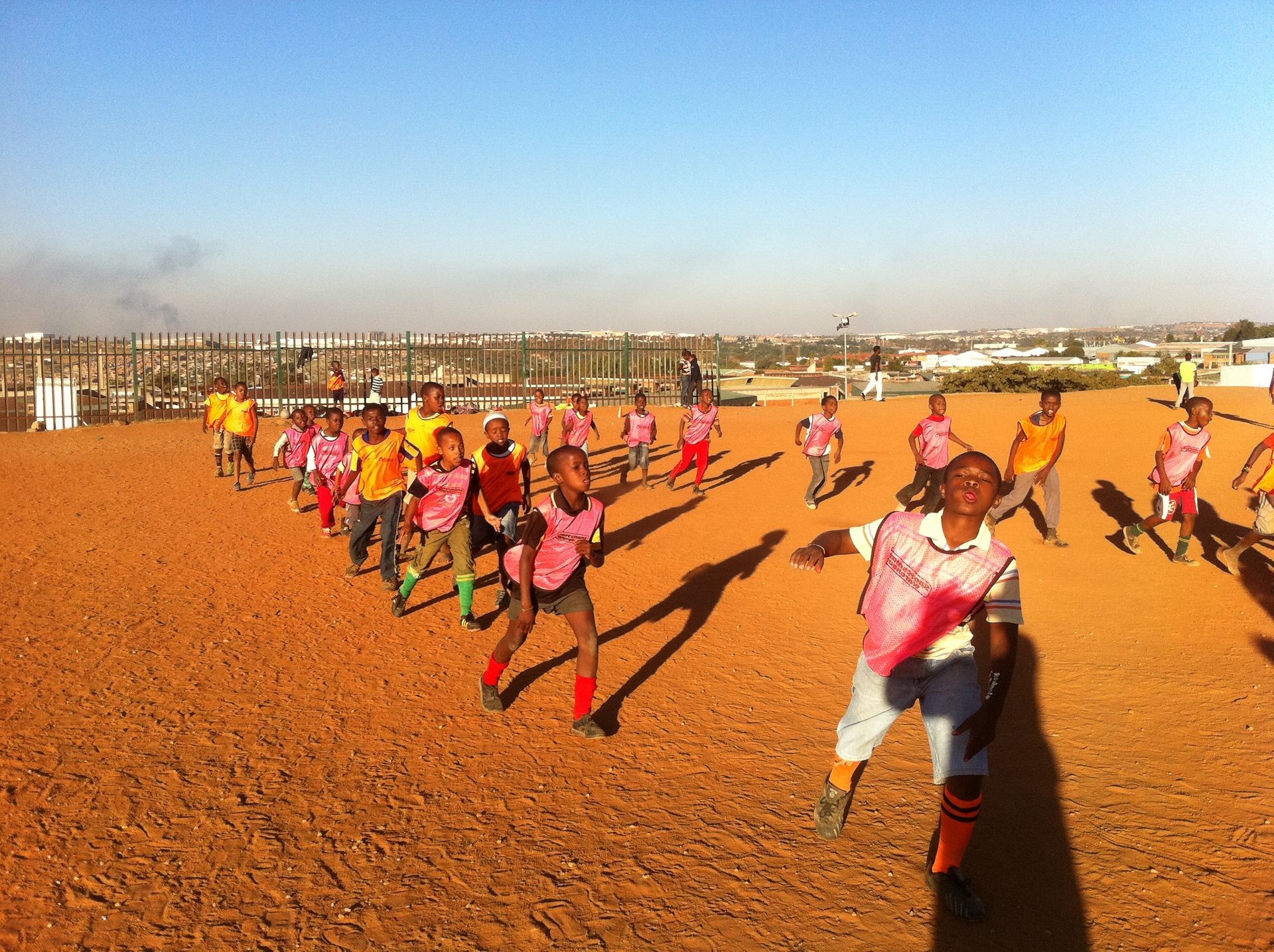 A group of children are running on a dirt field