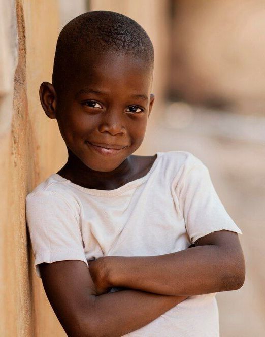 A young boy leaning against a wall with his arms crossed