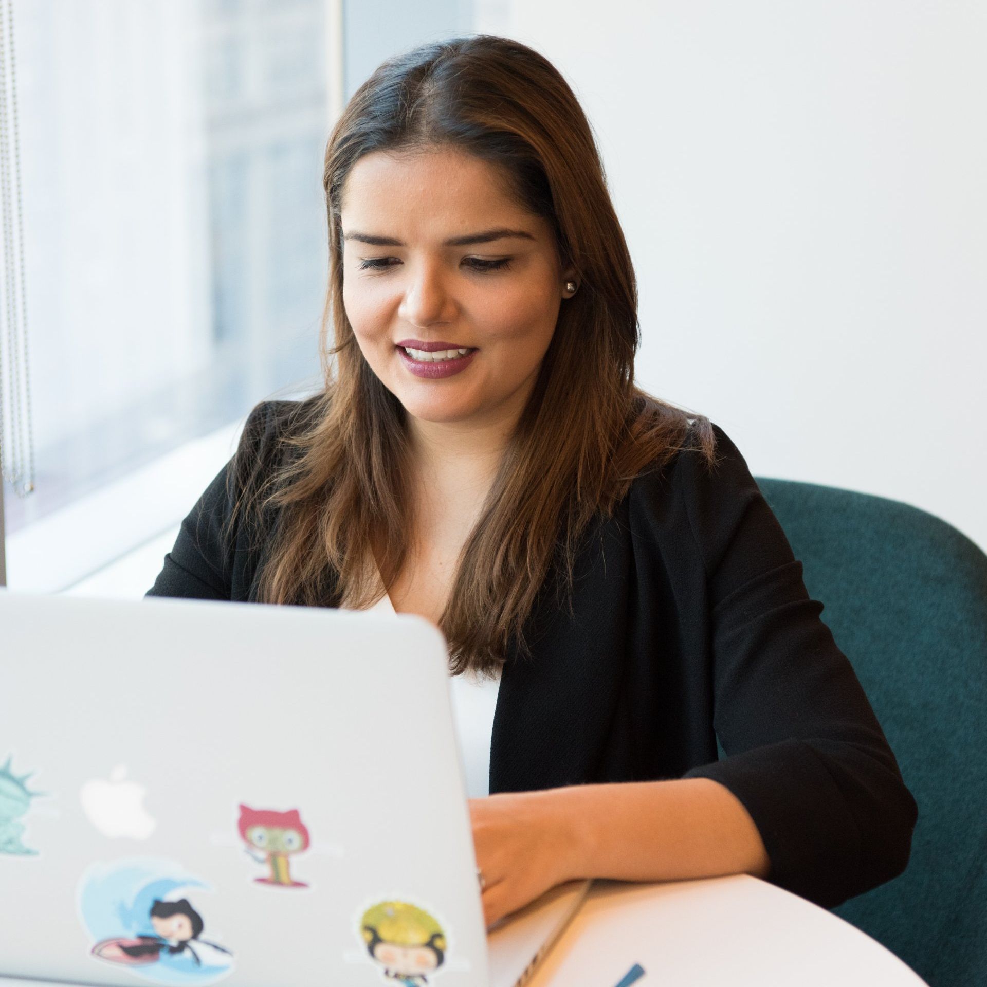 A woman is sitting at a table using an apple laptop