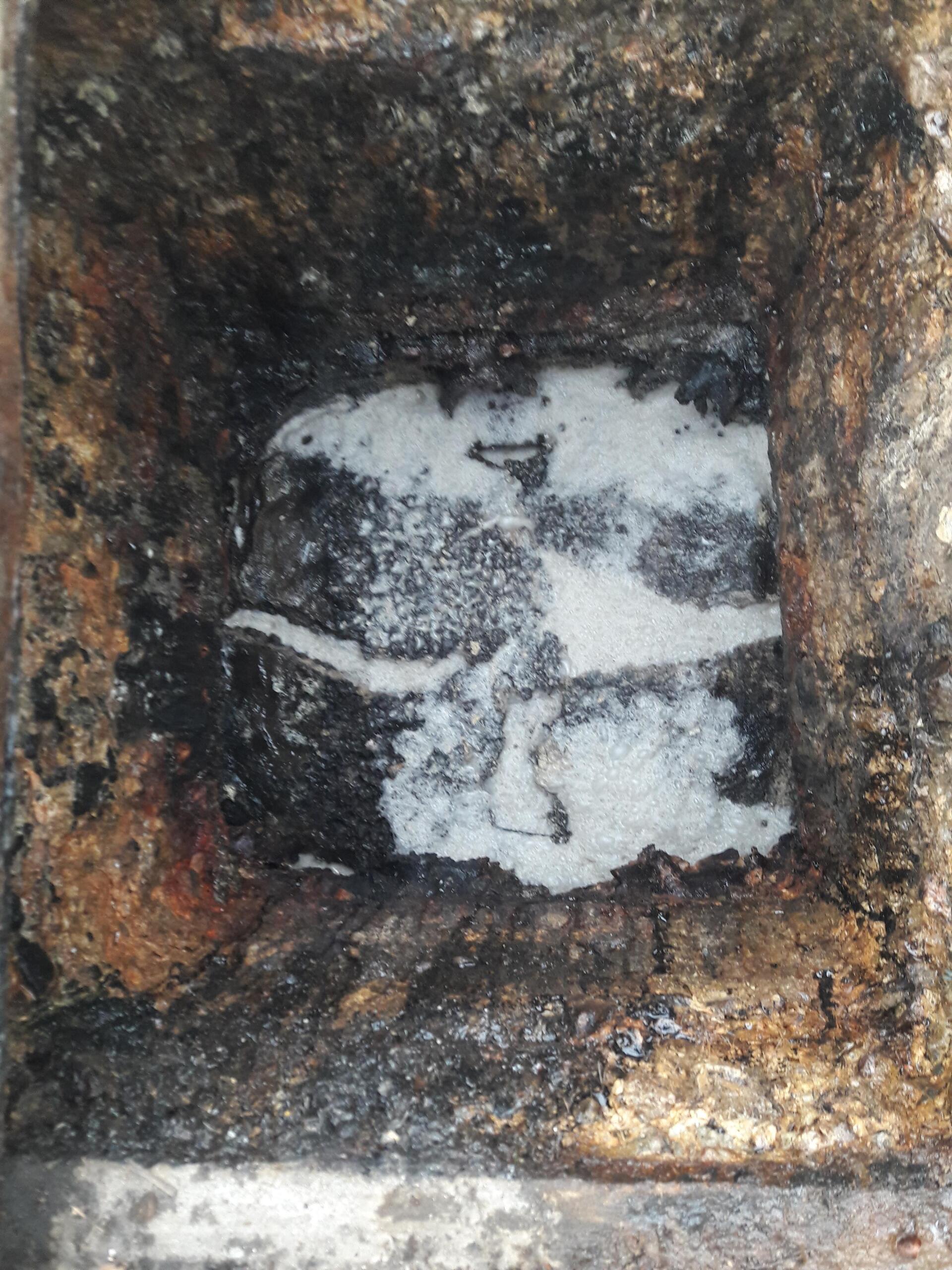 A close up of a hole in the ground with a white substance coming out of it.