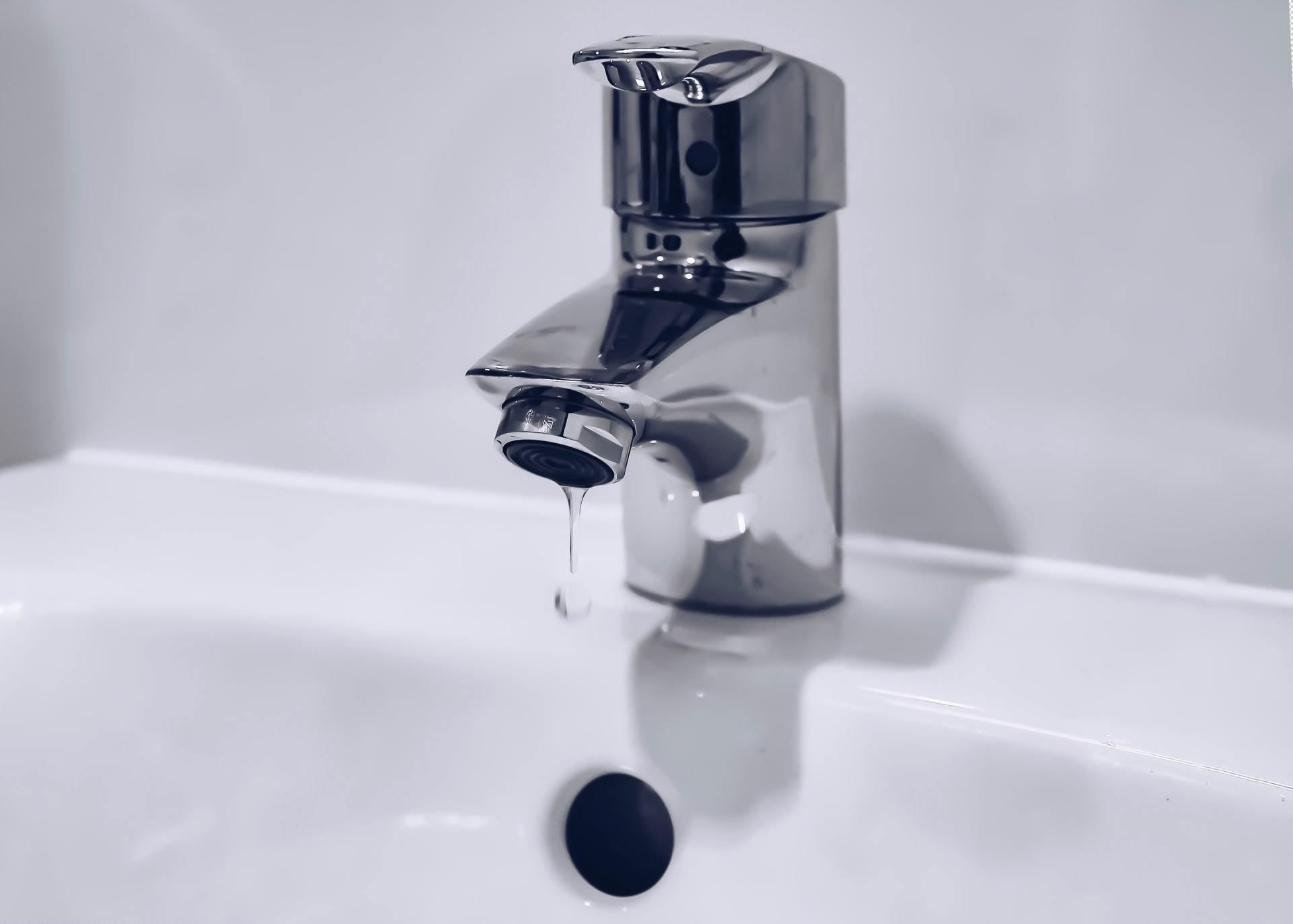 A close up of a bathroom sink with water dripping from the faucet.