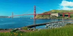 Golden Gate Bridge in San Francisco, California. Red bridge over blue water, green hills, boats docked.