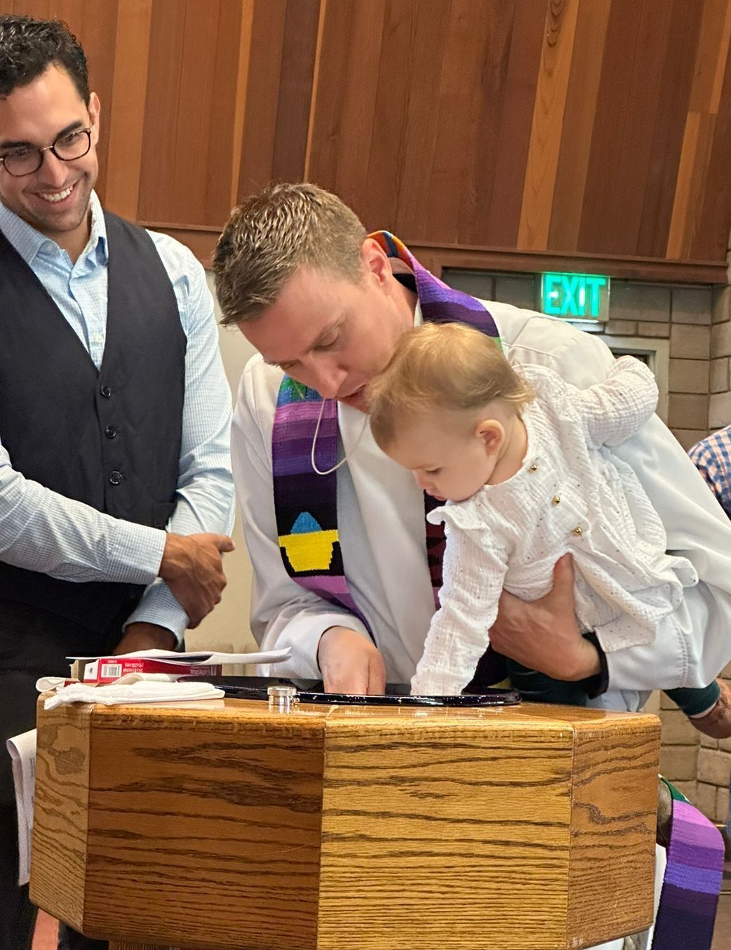 A man is holding a baby in his arms at a baptism.