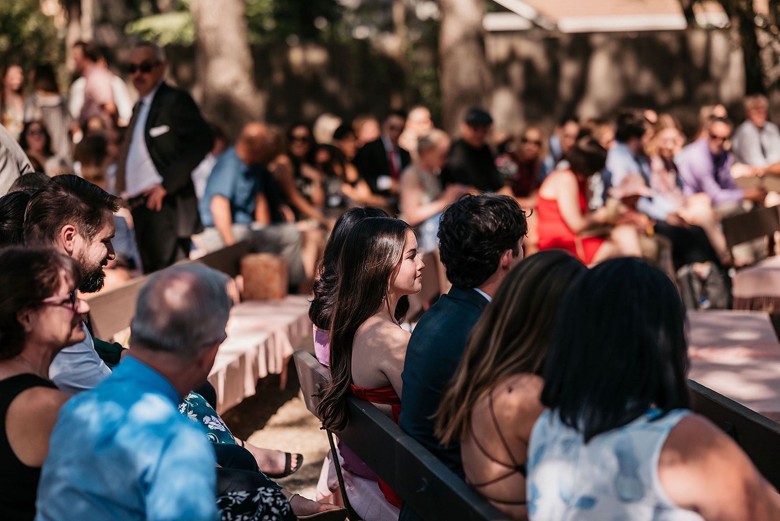 A group of people are sitting on benches at a wedding ceremony.