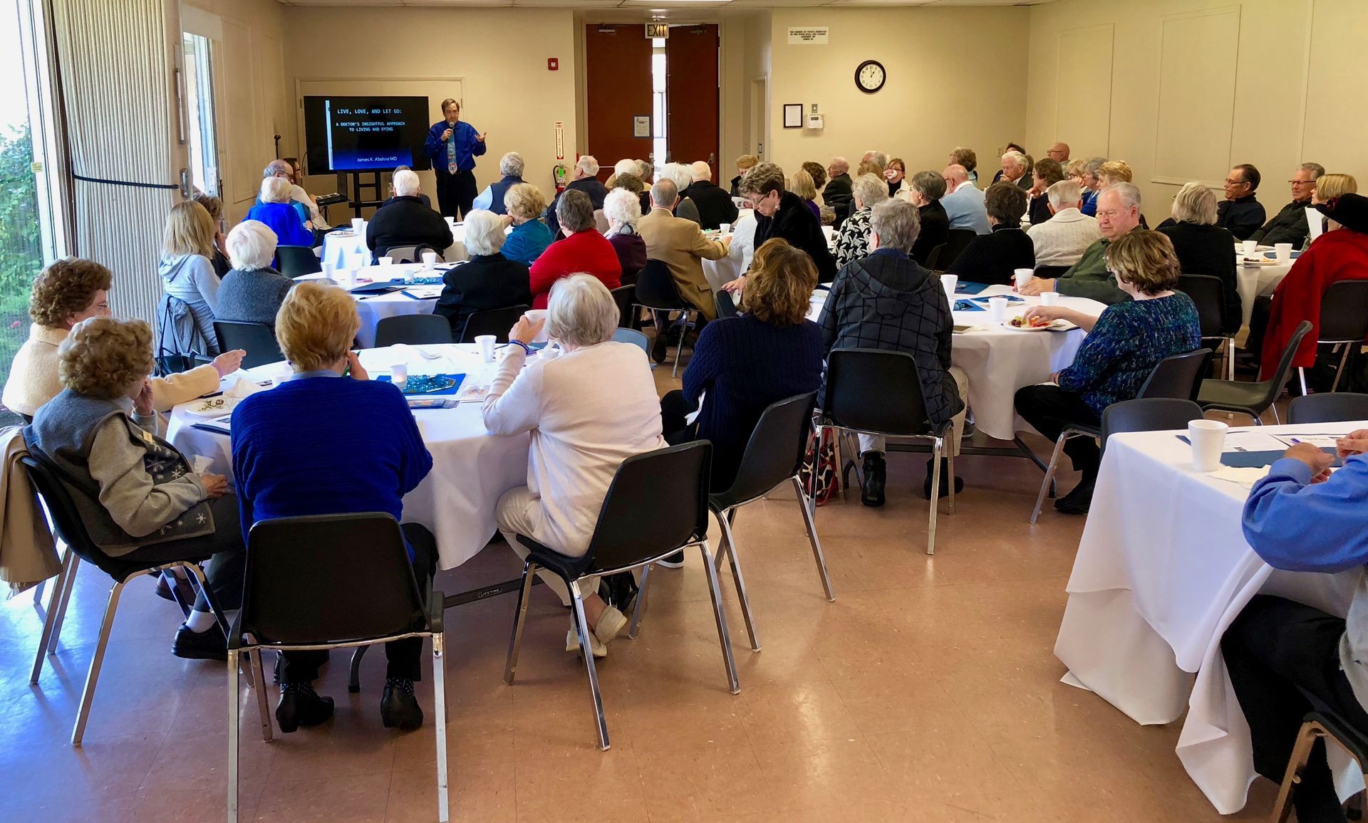 A large group of people are sitting at tables in a room.