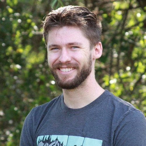 Ryko is wearing a gray shirt and smiling.