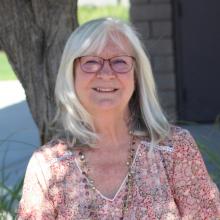 Kathy is sitting under a tree.