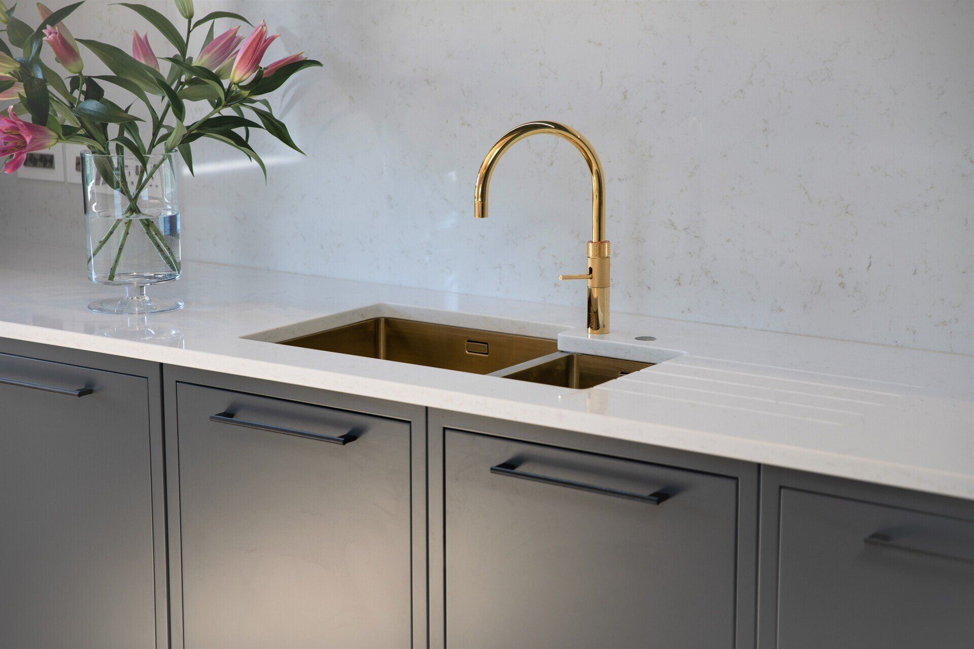 Enfield kitchen with gold quooker tap and large double gold sink with quartz drainer grooves and large vase with lilies