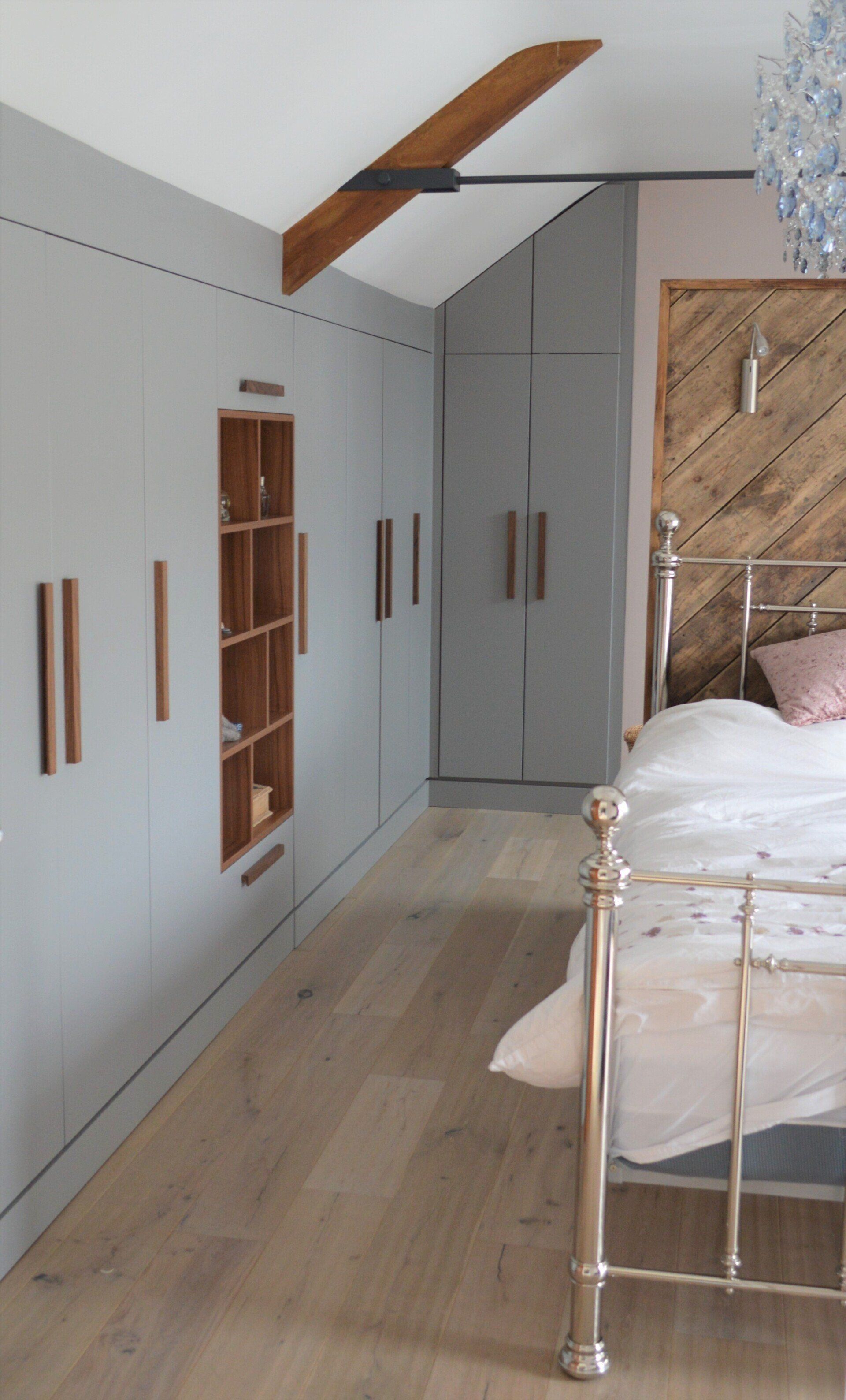 Bespoke wardrobe in walnut and light grey with open unit for display, including angled wardrobes and light wood floor with metal frame bed