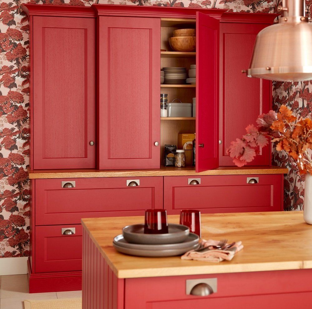 Red dresser with pan drawers displaying pantry goods and island with a wooden worktop