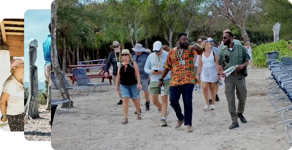 Group of tourists on a sandy path, guided by two men, near trees and wooden structures.